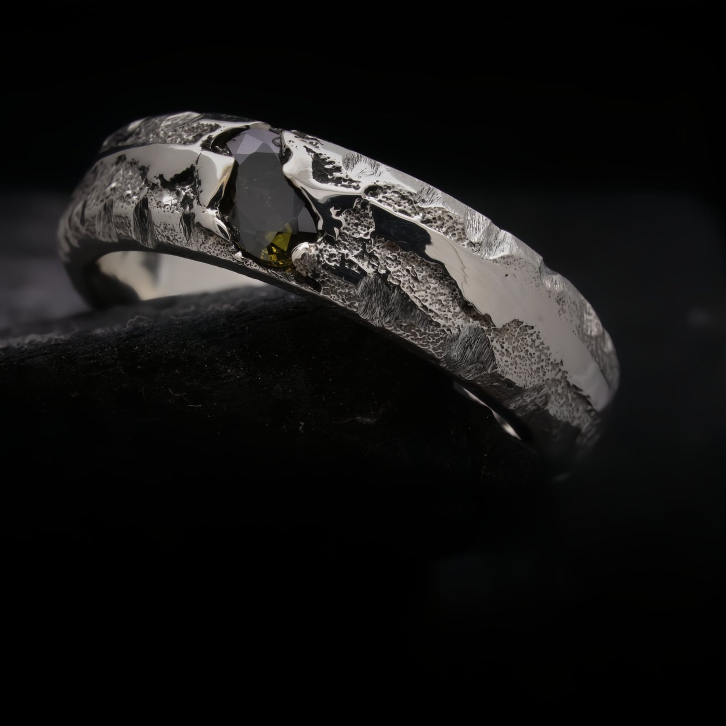 Anillo de compromiso artesanal con piedra verde peridoto y acabado irregular.