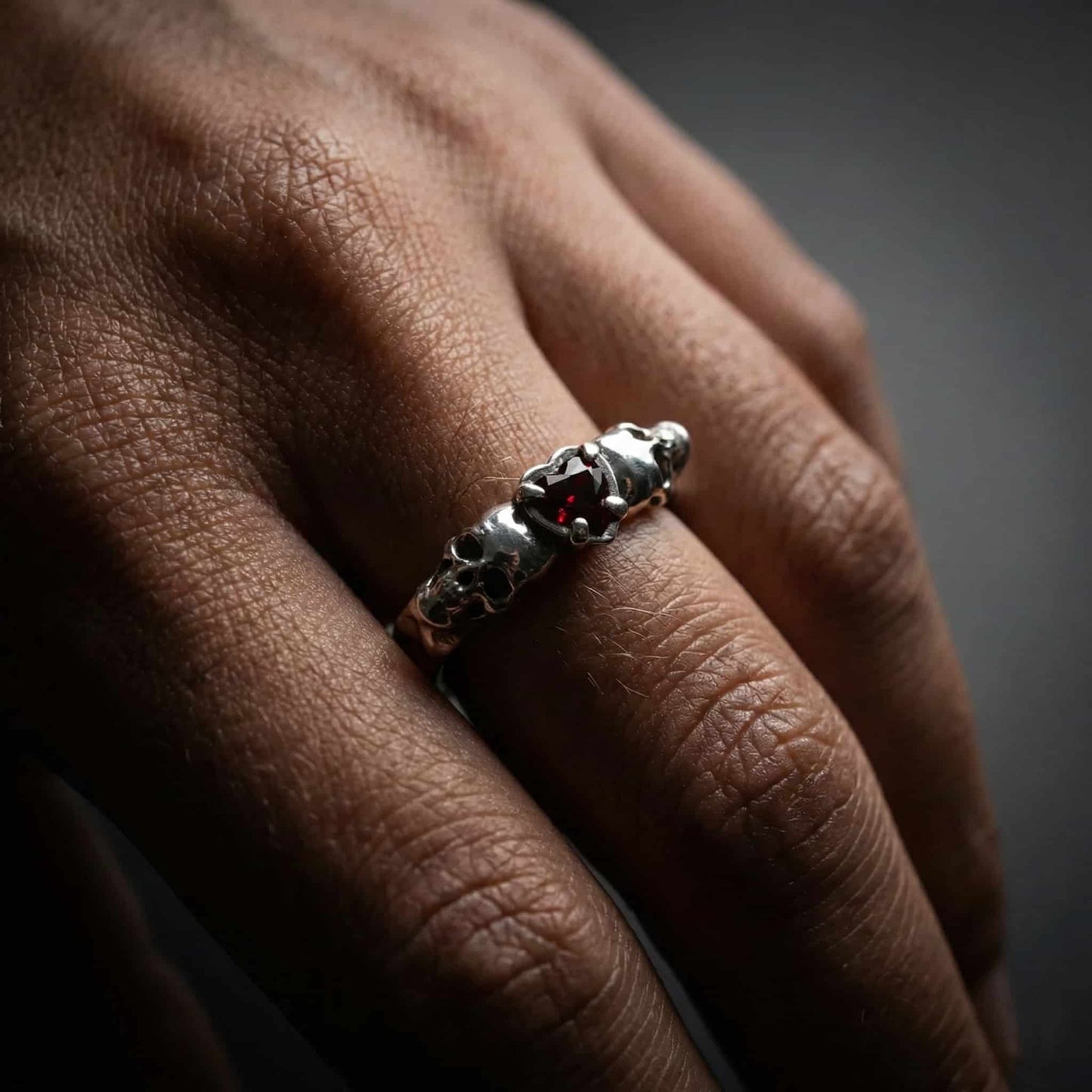 Mano de mujer luciendo anillo de plata y granate.