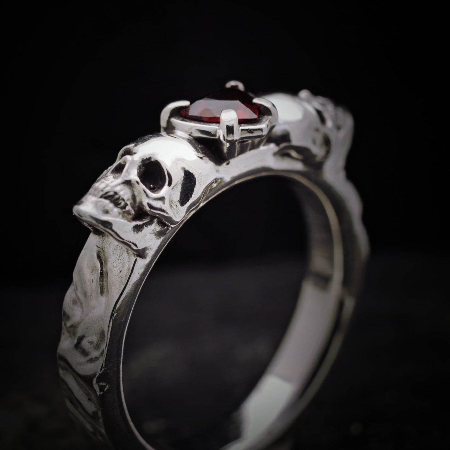 Anillo con granate natural con forma de corazon y dos calaveras de plata para hombre