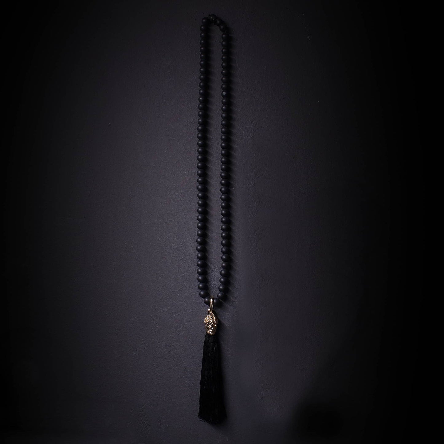 Collar largo de onix mate con colgante dorado de calavera y tasel negro