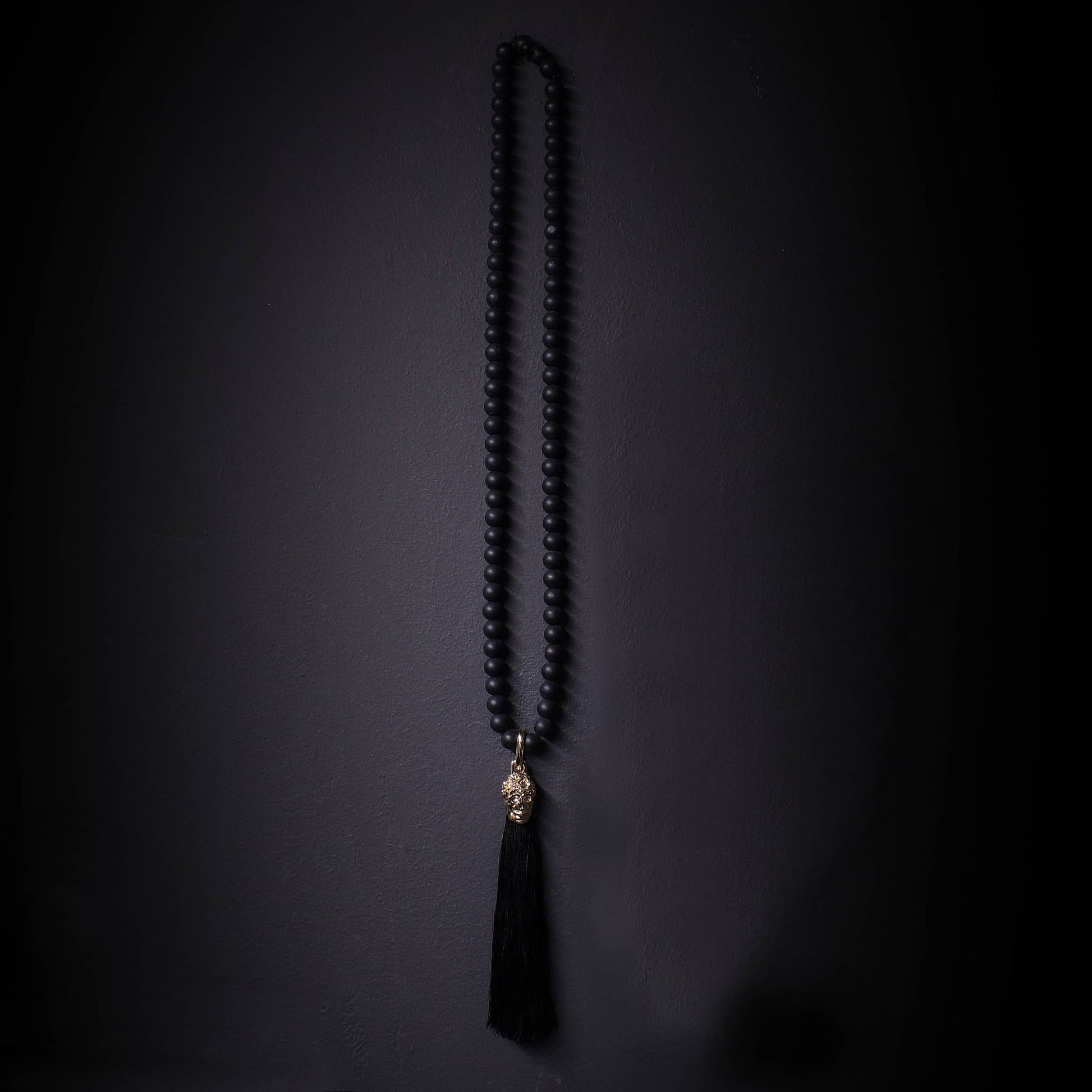Collar largo de onix mate con colgante dorado de calavera y tasel negro