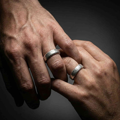 Alianza ancha para hombre puesta en la mano con acabado brillante texturizado.