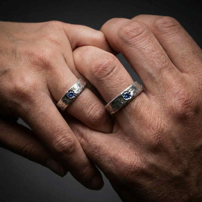 Alianza Estérope con piedra azul puesto en mano, diseño robusto.