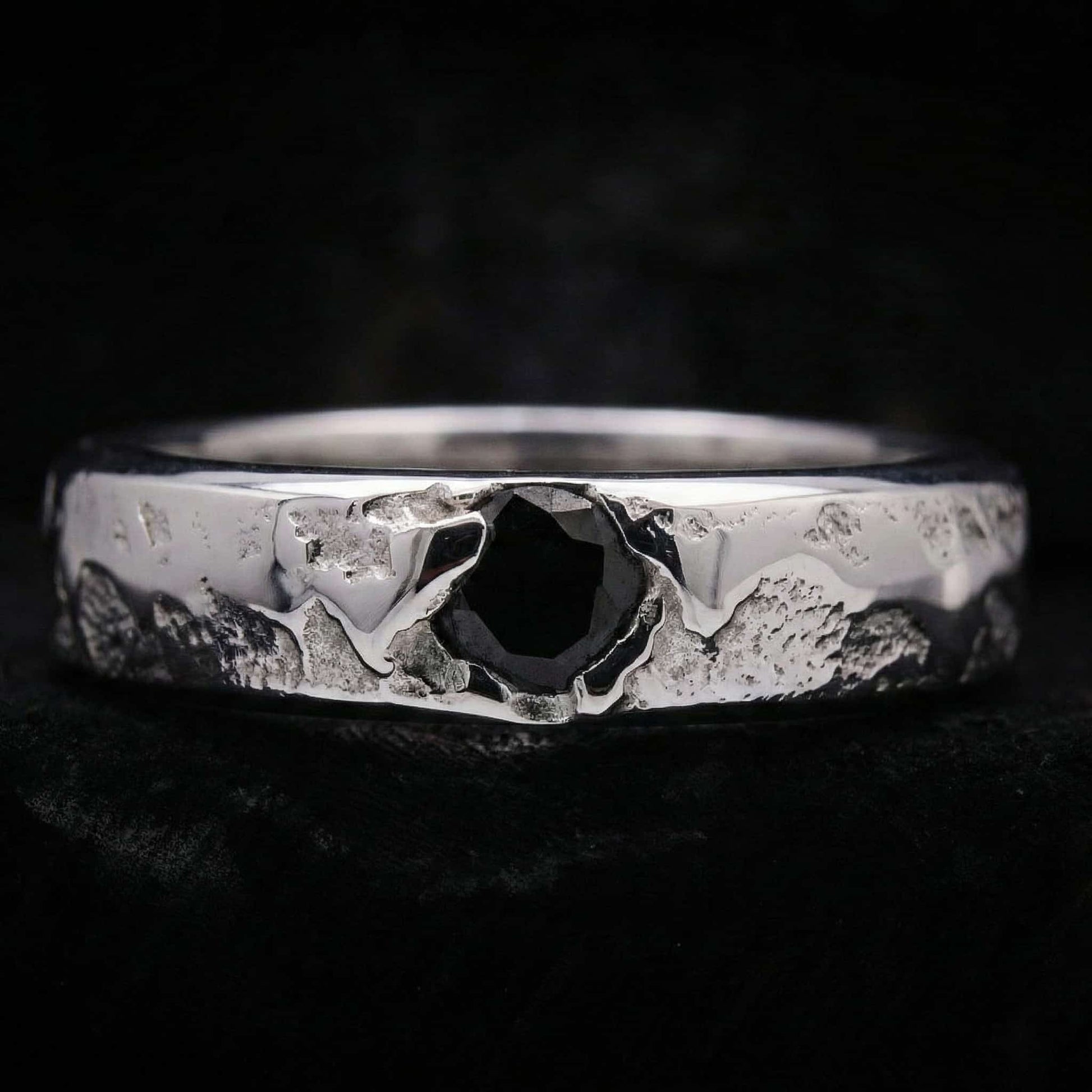 Alianza de plata maciza artesanal con circonita negra y textura rústica de fundición.