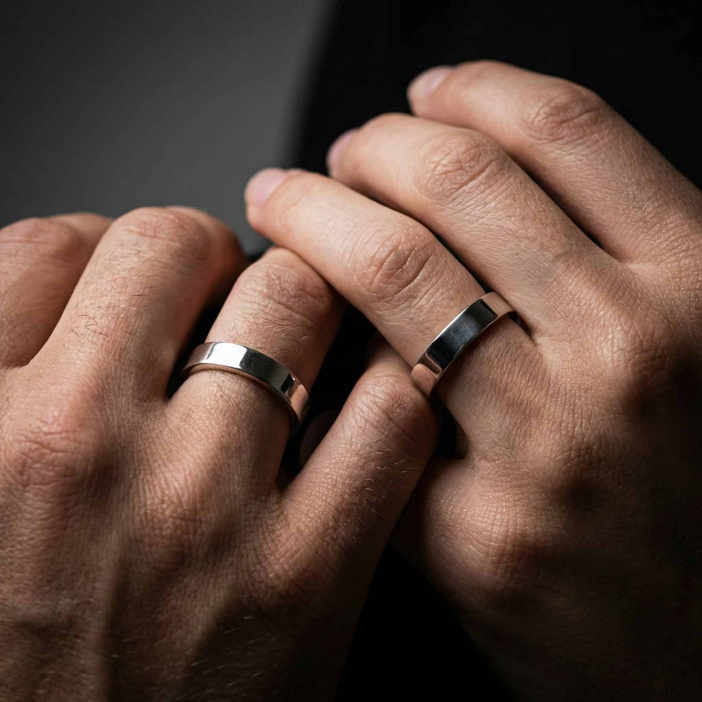 Alianza moderna de forma cuadrada puesta en mano masculina.