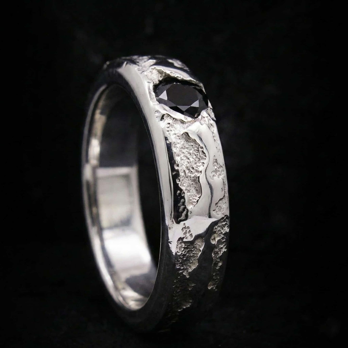 Alianza de plata maciza artesanal con circonita negra y textura rústica de fundición.