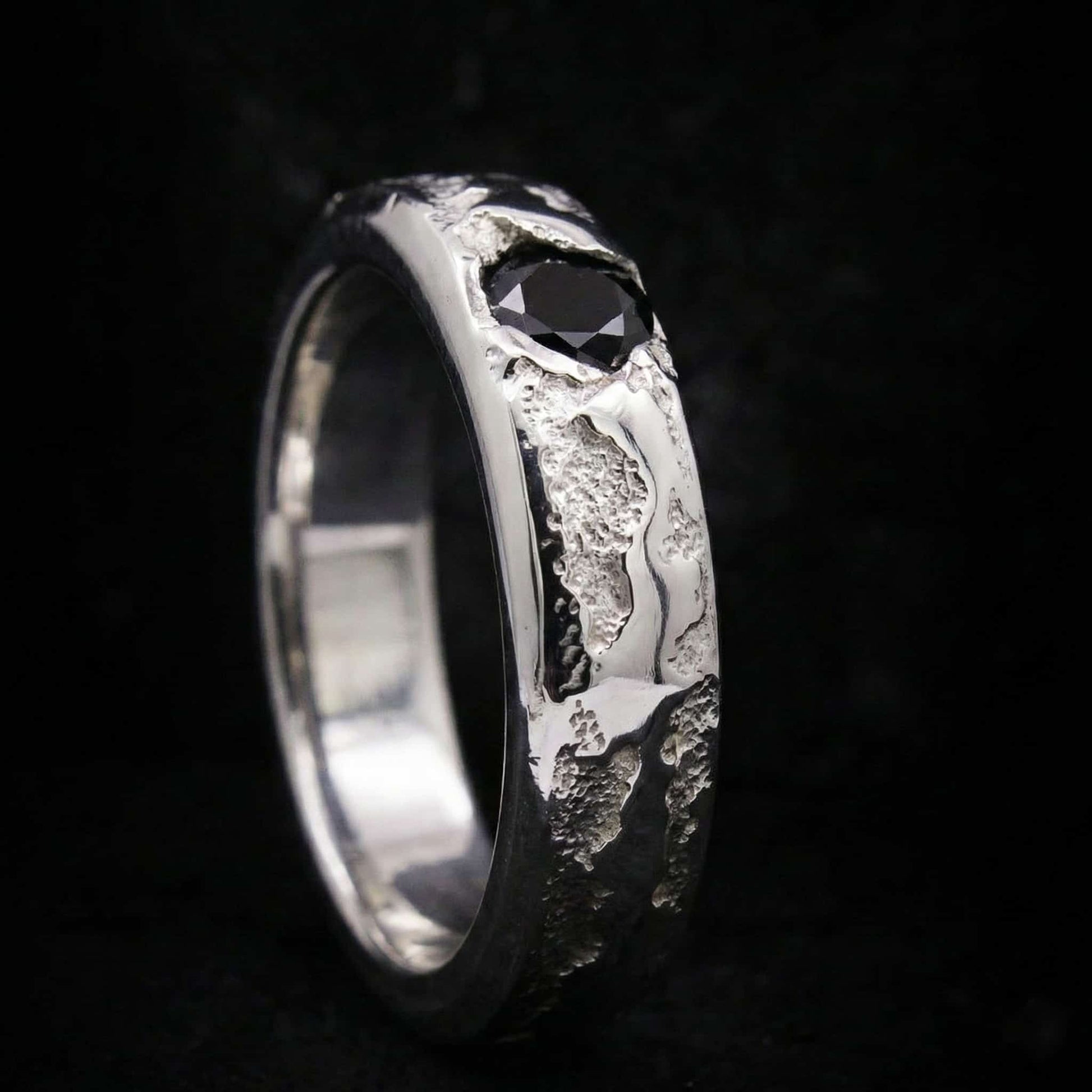 Alianza de plata maciza artesanal con circonita negra y textura rústica de fundición.