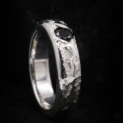 Alianza de plata maciza artesanal con circonita negra y textura rústica de fundición.