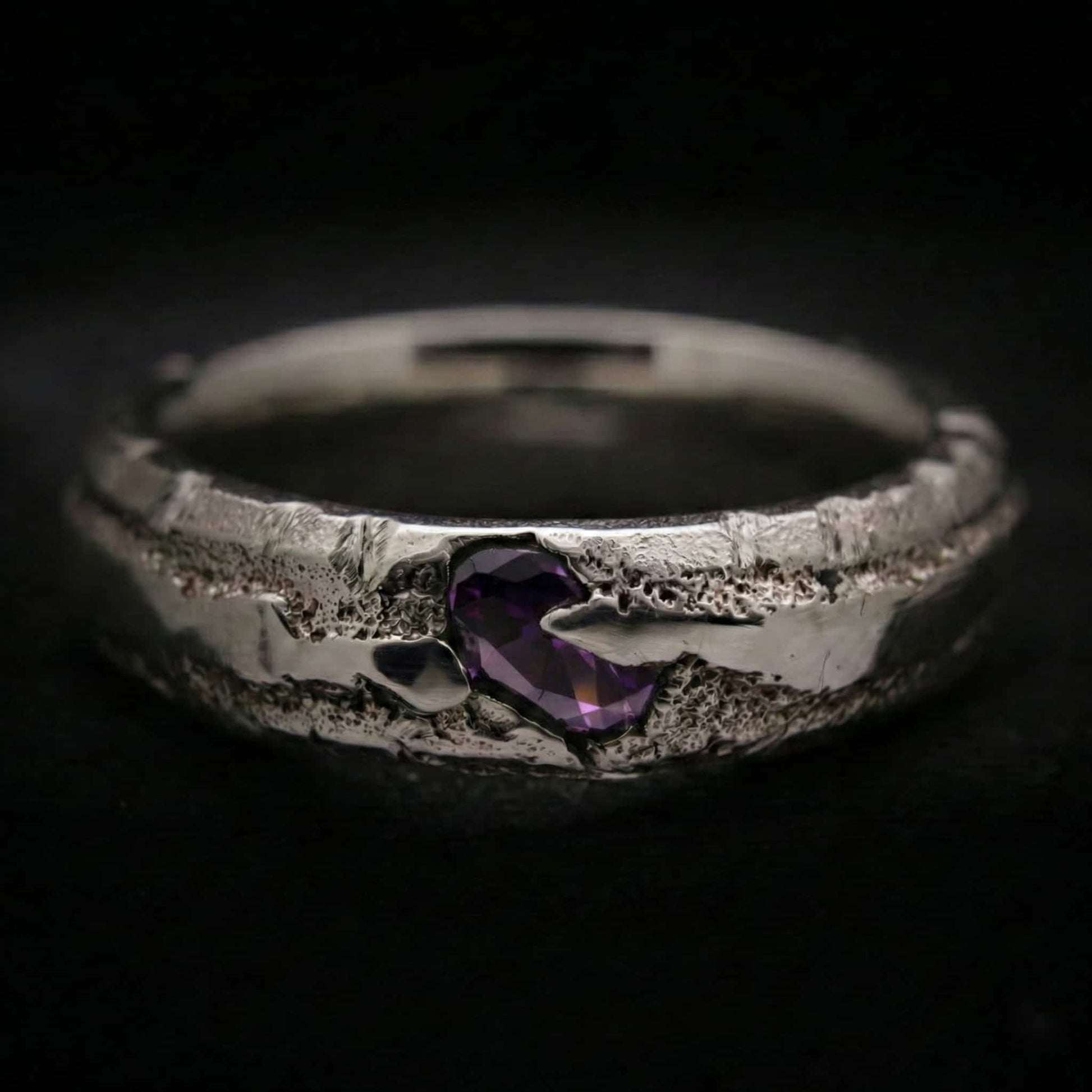 Alianza de plata maciza con textura rústica y circonita color amatista. Anillo de 5mm de ancho y 3mm de grosor hecho a mano por fundición en arena.