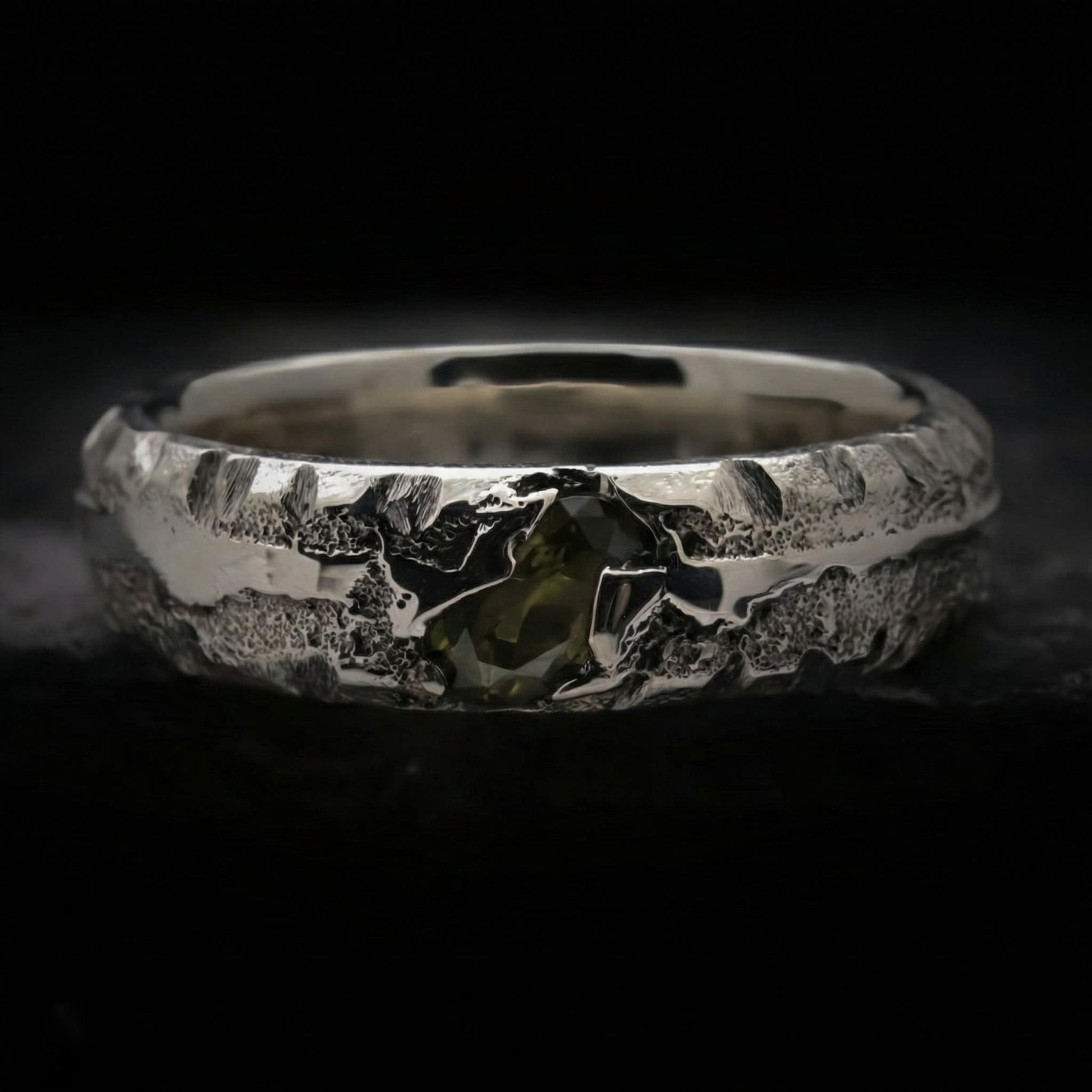 Alianza de plata maciza con textura rústica y circonita color verde oliva. Anillo de 5mm de ancho y 3mm de grosor hecho a mano por fundición en arena.