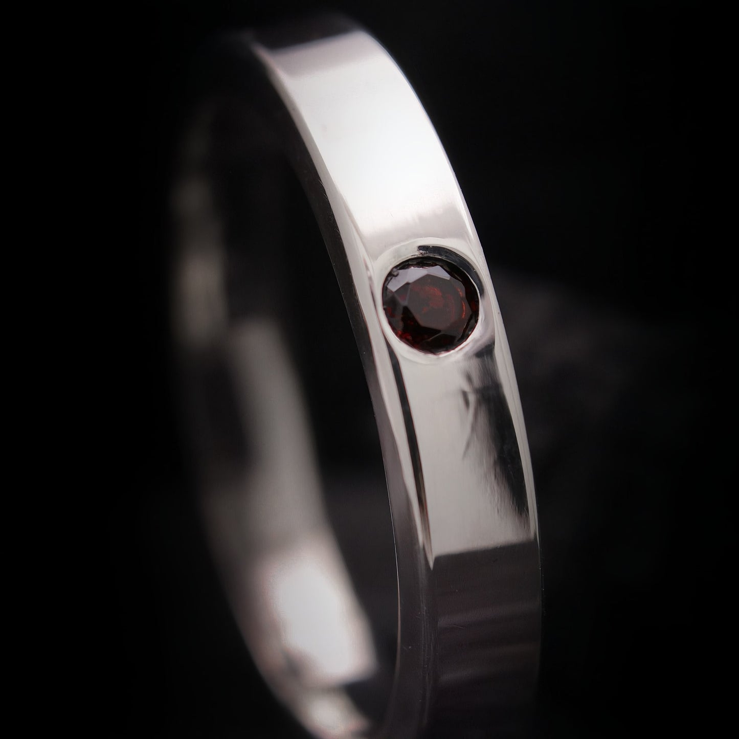 Anillo fino de plata para hombre con acabado pulido y  piedra roja.