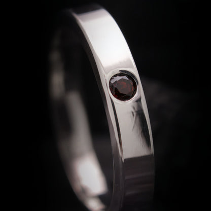 Anillo fino de plata para hombre con acabado pulido y  piedra roja.