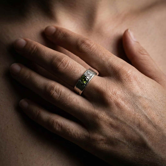 Mano de modelo luciendo el anillo de la colección Legado con cenizas y circonita peridoto en el dedo.