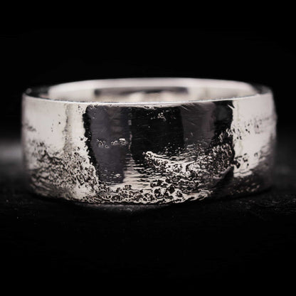 Anillo de plata de 10mm de ancho para hombre con acabado textura arena irregular y superficie brillante.