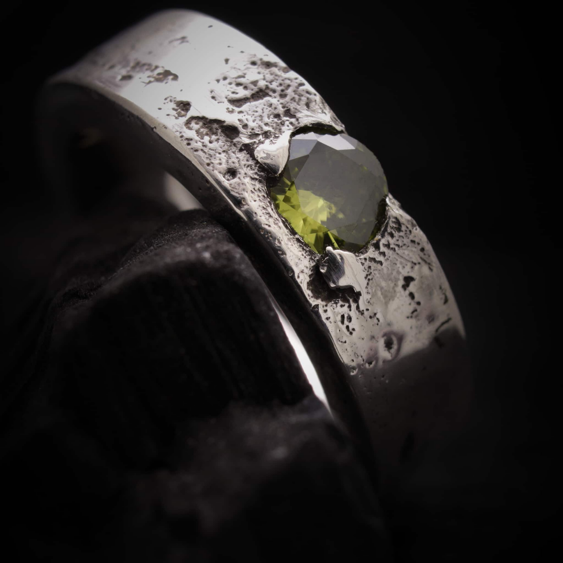 Detalle del anillo Legado con incrustación de cenizas y piedra circonita color verde peridoto.
