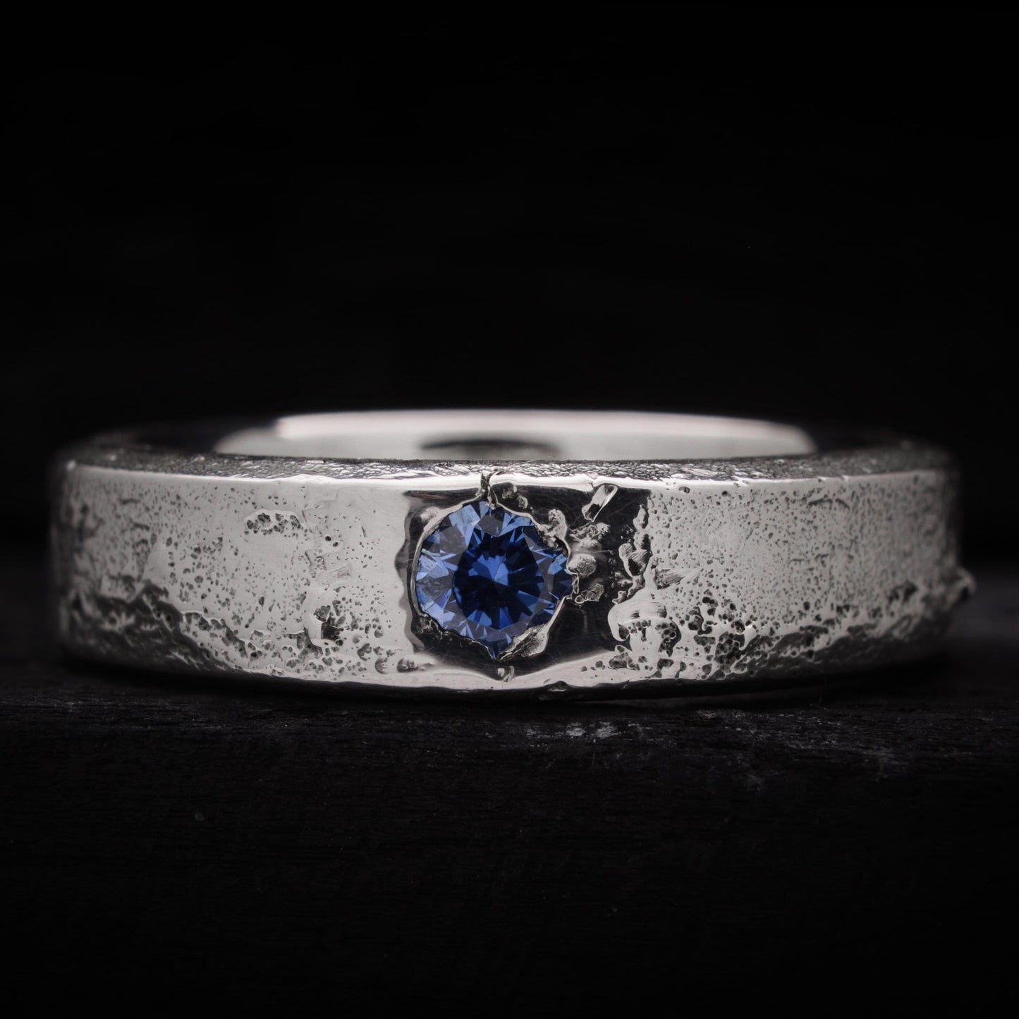 Anillo de plata para hombre forjado en arena con una circonita azul brillante incrustada
