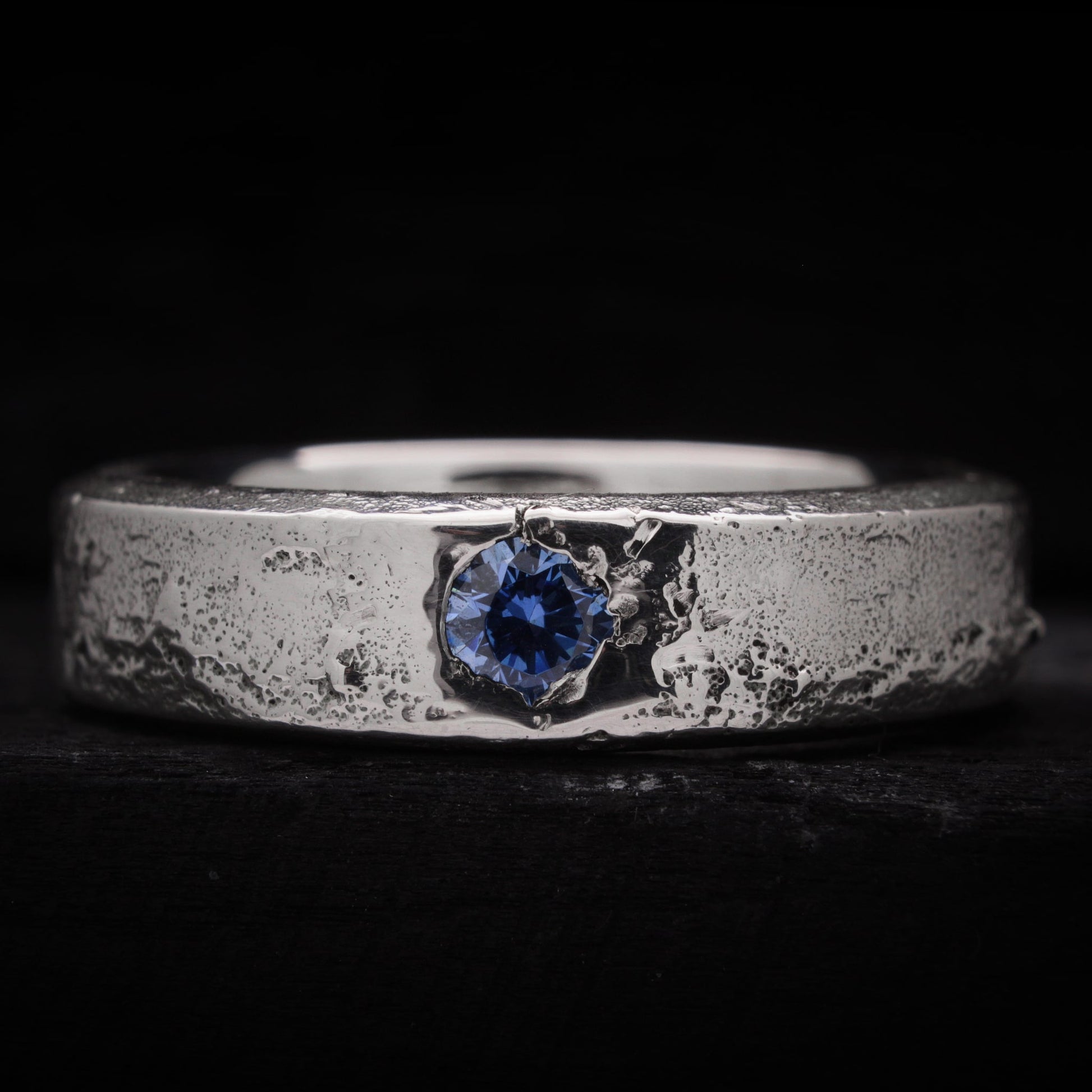 Anillo de plata para hombre forjado en arena con una circonita azul brillante incrustada