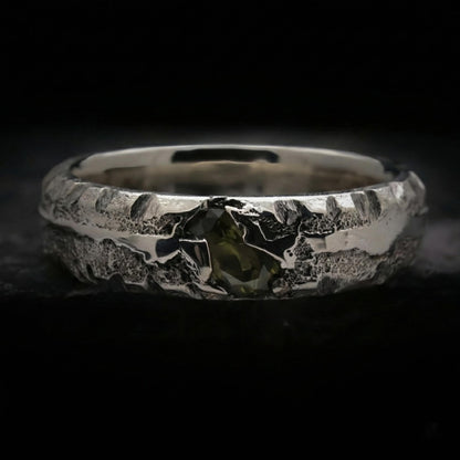 Detalle de anillo para hombre con circonita verde peridoto de plata con textura rústica.