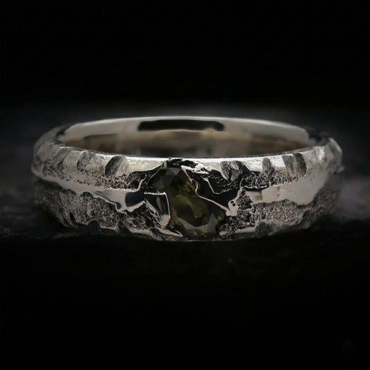 Detalle de anillo para hombre con circonita verde peridoto de plata con textura rústica.