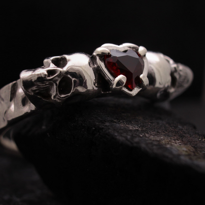 Anillo de plata para mujer diseño calaveras con piedra corazón de granate vista frontal.