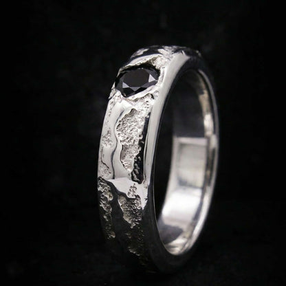 Vista lateral de anillo tipo sello de plata maciza con acabado texturizado y piedra negra incrustada.