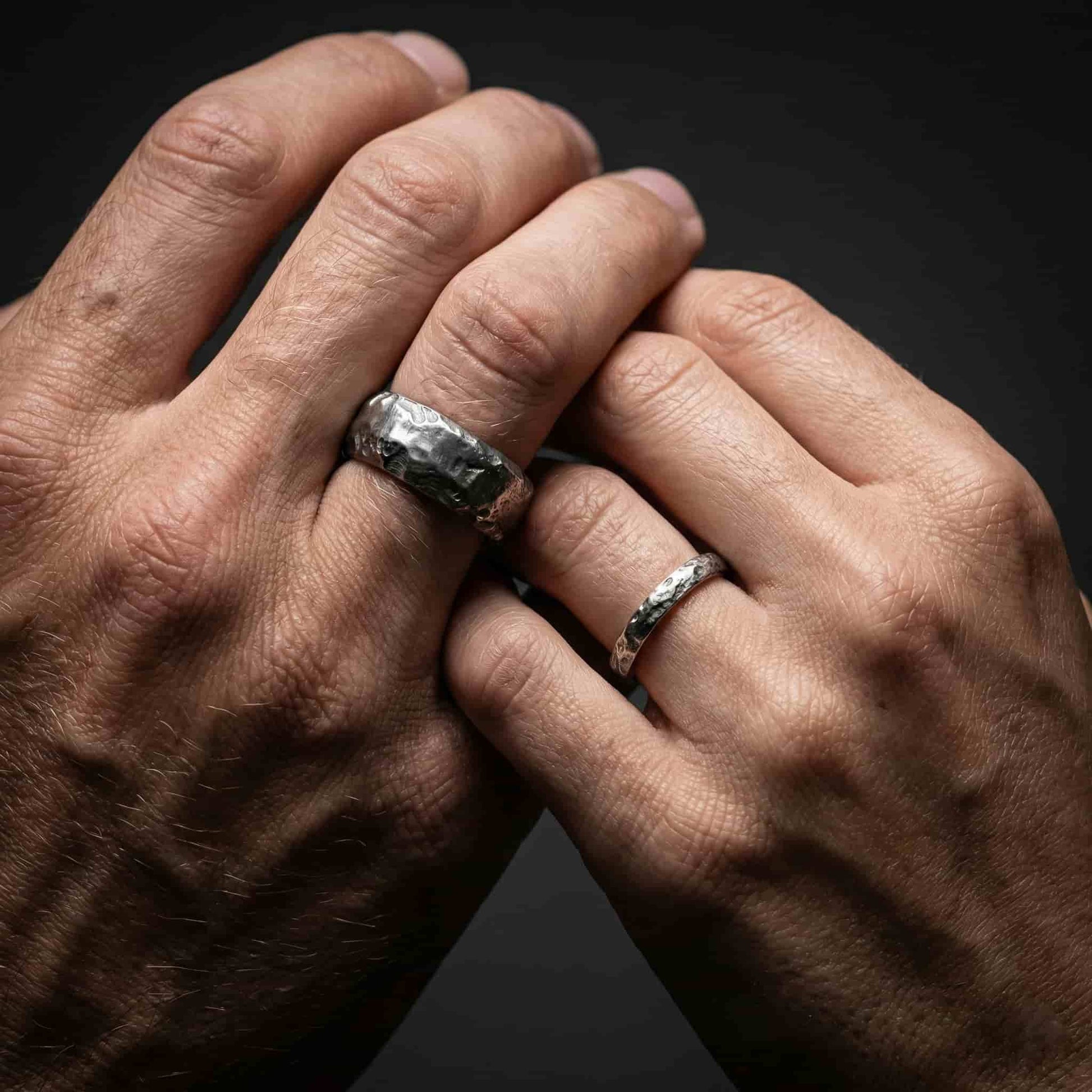 Pareja en boda rústica con alianzas originales de plata negra y textura orgánica.