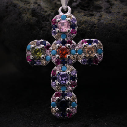 Cruz de plata con detalles de piedras coloridas y estilo llamativo