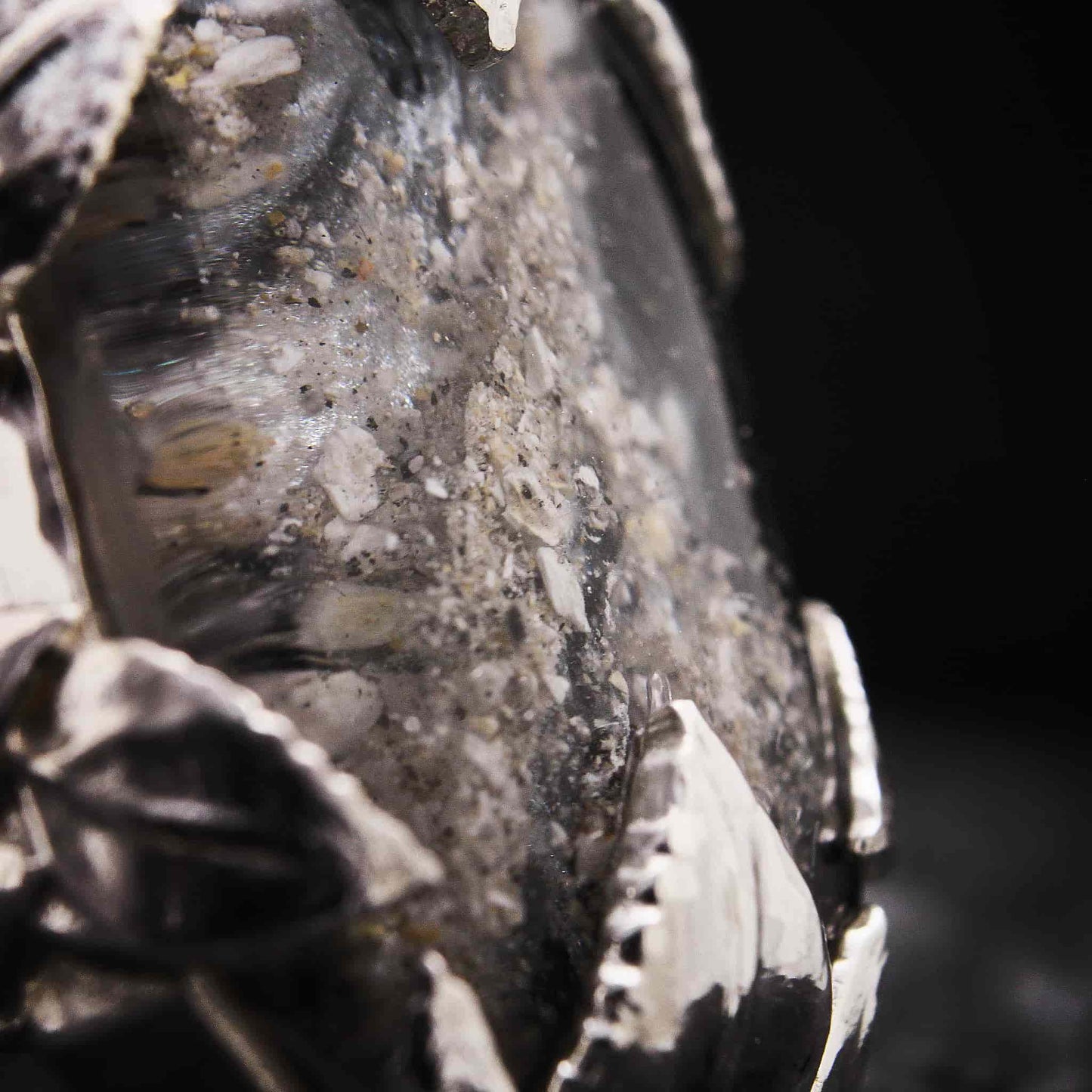 Primer plano de resina con cenizas encapsuladas en anillo de plata artesanal.