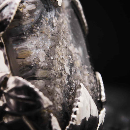 Primer plano de resina con cenizas encapsuladas en anillo de plata artesanal.