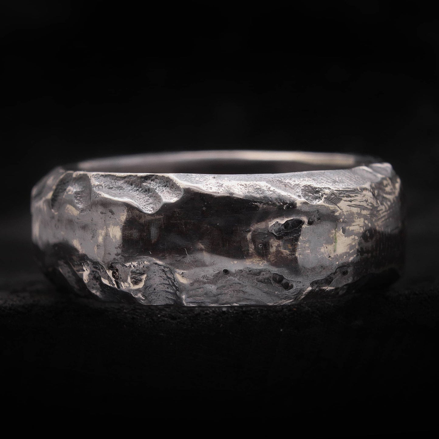 Macro de textura cráter irregular en anillo de plata envejecida artesanal.