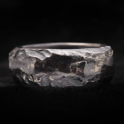 Macro de textura cráter irregular en anillo de plata envejecida artesanal.