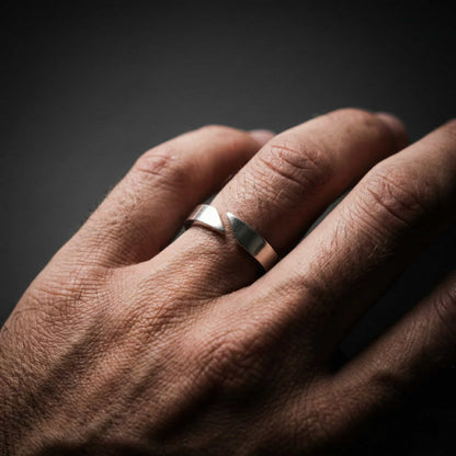 Hombre tocándose el cuello luciendo un anillo de plata abierto de estilo minimalista y elegante.