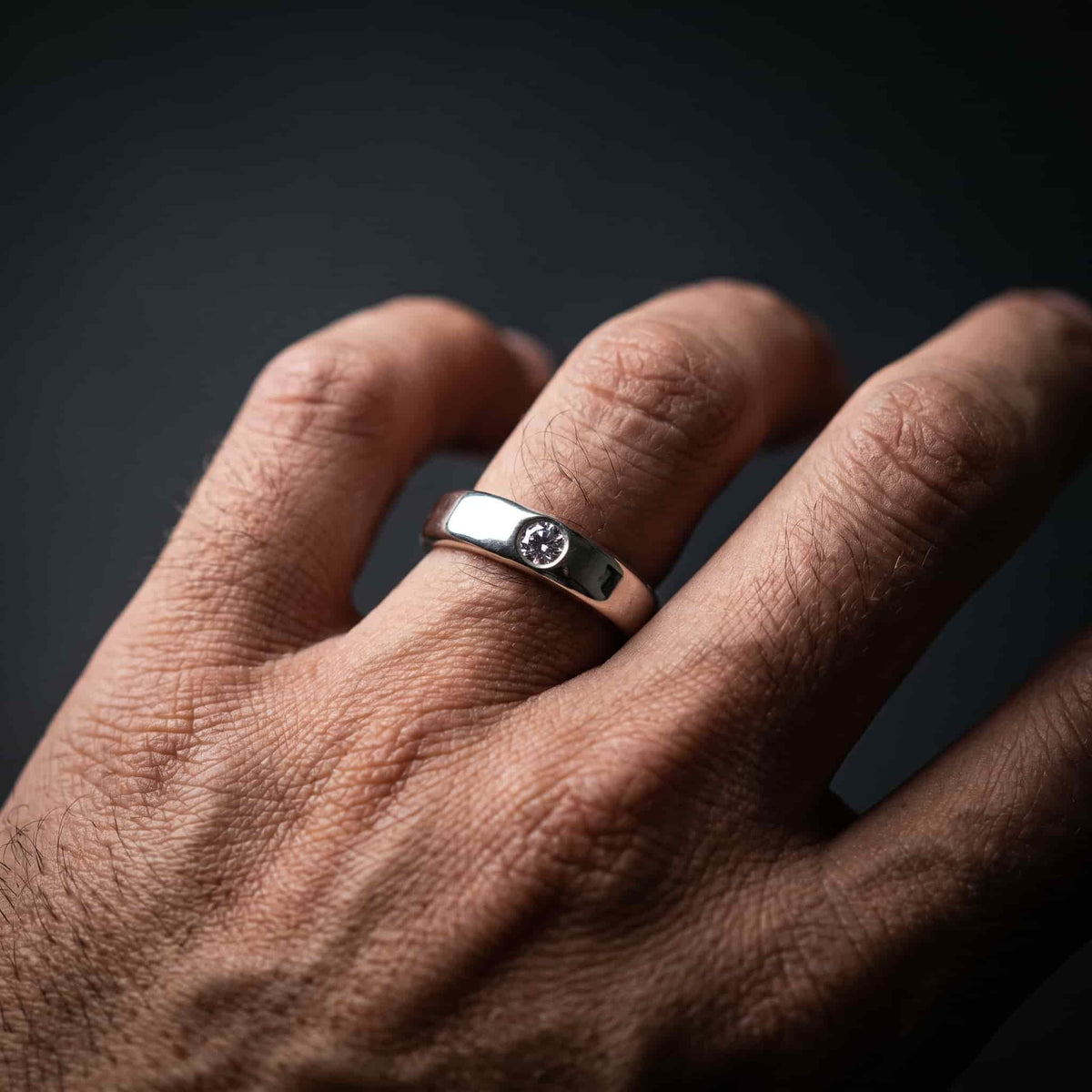 Hombre llevando la alianza de luto de 4mm con circonita. Anillo robusto, discreto y hermético al agua.