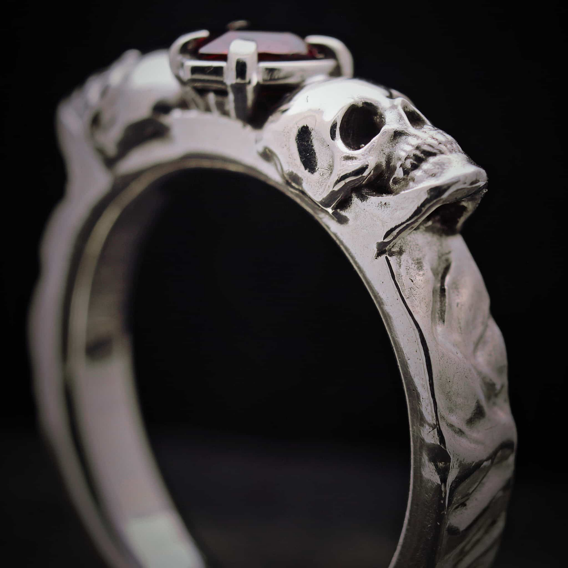 Anillo robusto de plata maciza estilo memento mori con calaveras laterales.