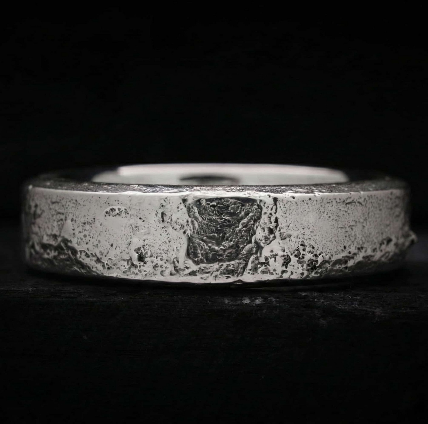 Interior pulido y cómodo del anillo memorial Lur, contrastando con su exterior de plata forjada en arena.