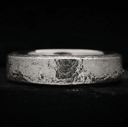 Interior pulido y cómodo del anillo memorial Lur, contrastando con su exterior de plata forjada en arena.