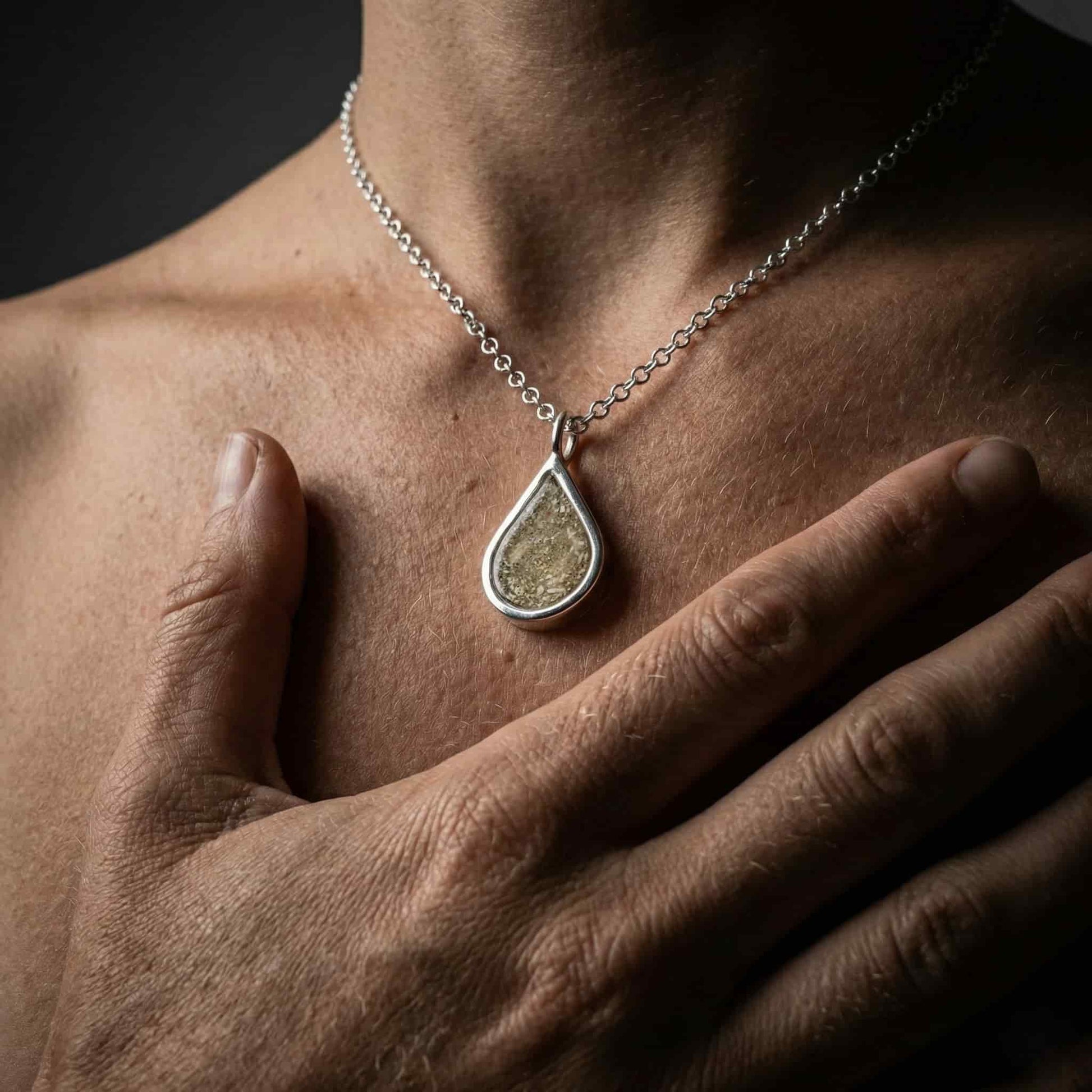 Collar de joyería conmemorativa artesanal de K2 Jewels, mostrando un colgante de plata con cenizas incrustadas usado por una persona.