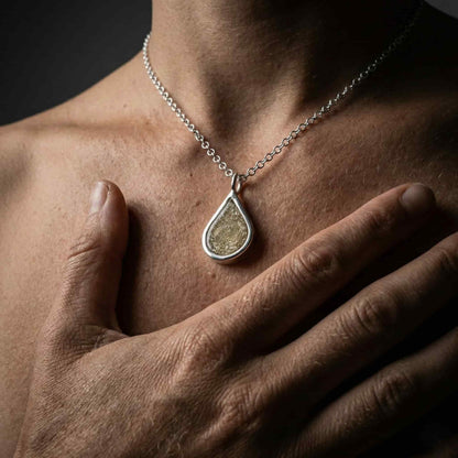 Collar de joyería conmemorativa artesanal de K2 Jewels, mostrando un colgante de plata con cenizas incrustadas usado por una persona.