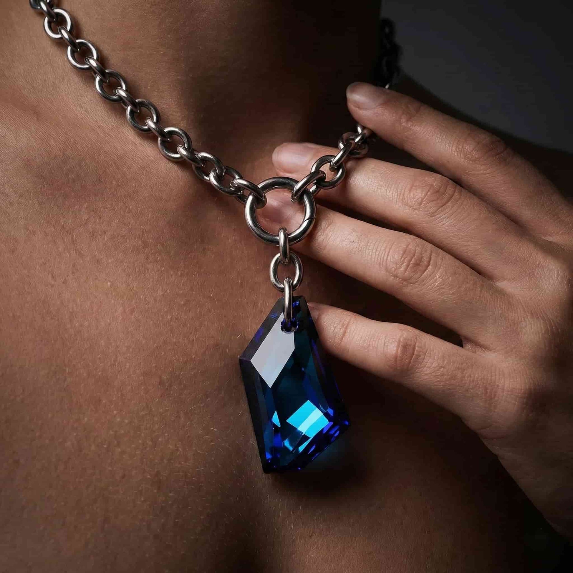 Mujer luciendo collar de eslabones grandes de acero con piedra azul en el cuello.