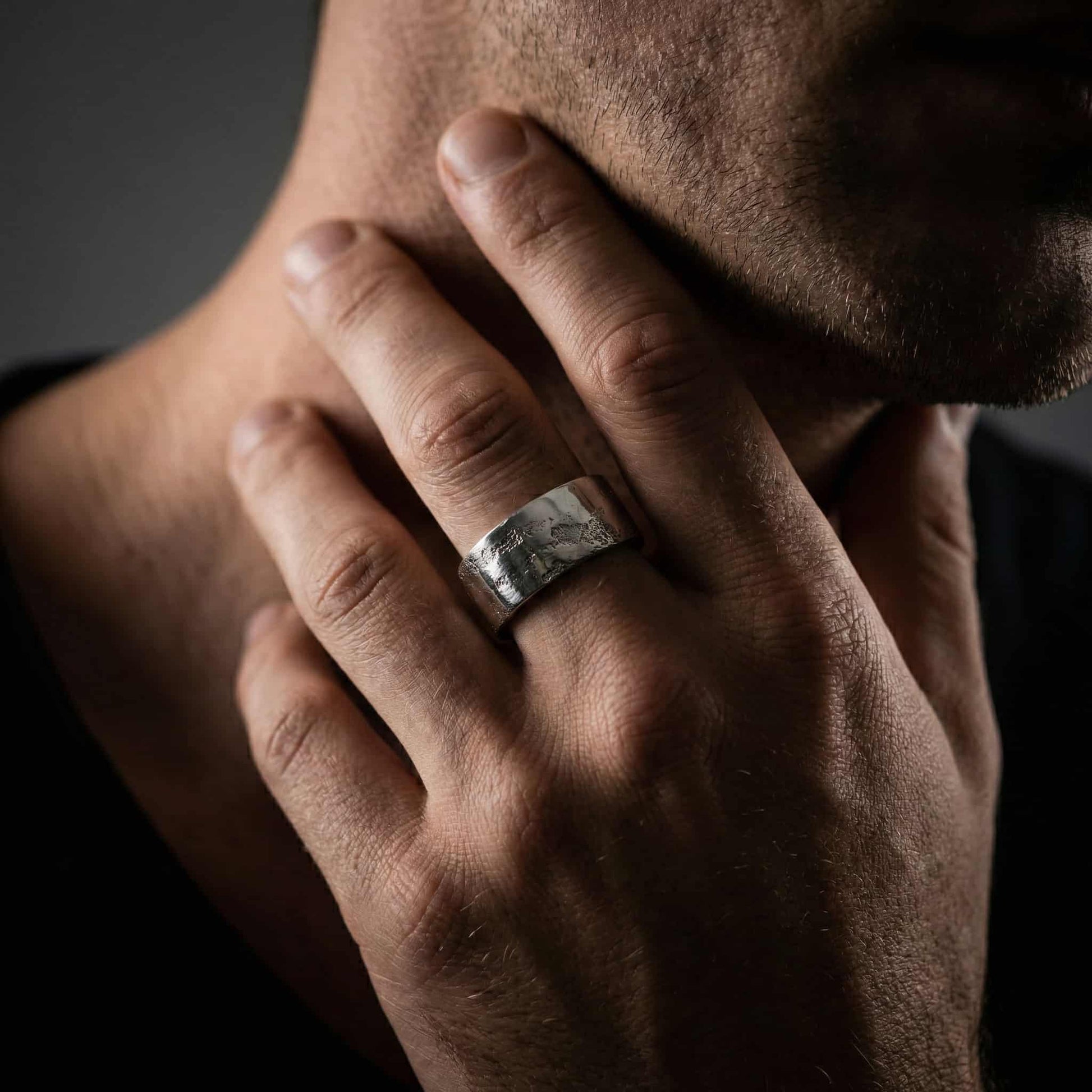 Mano de hombre luciendo el anillo de banda ancha de 10mm en el dedo anular, estilo casual.