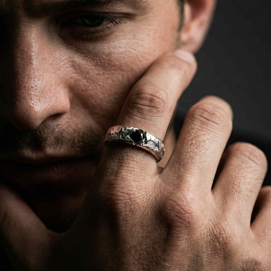 Hombre con estilo llevando el anillo de plata artesanal texturizado con circonita negra en la mano.