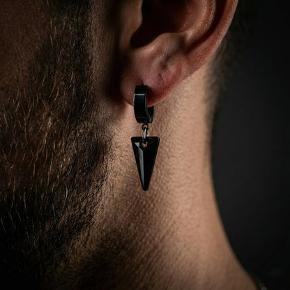 Hombre joven llevando pendiente de acero y cristal con estilo urbano casual.