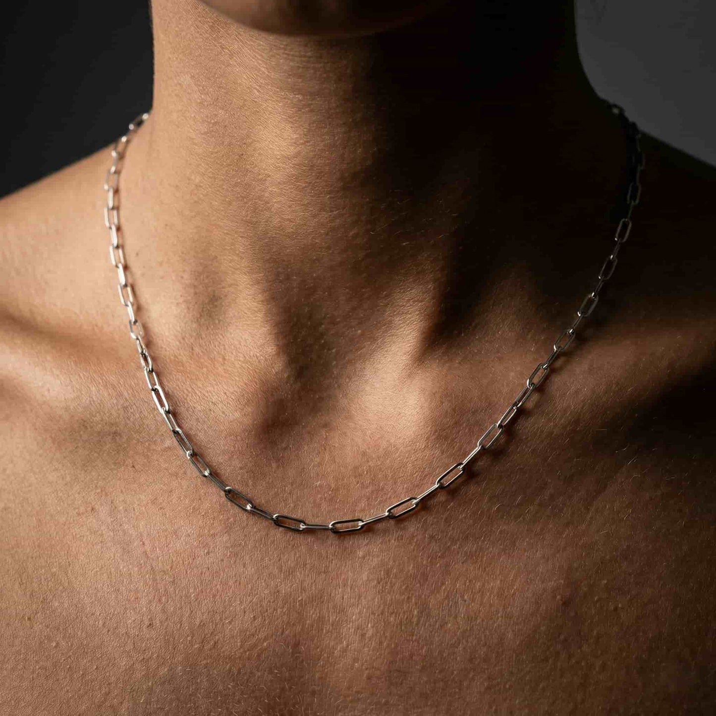 Mujer vistiendo cadena de plata con eslabón rectangular combinada con camiseta básica.