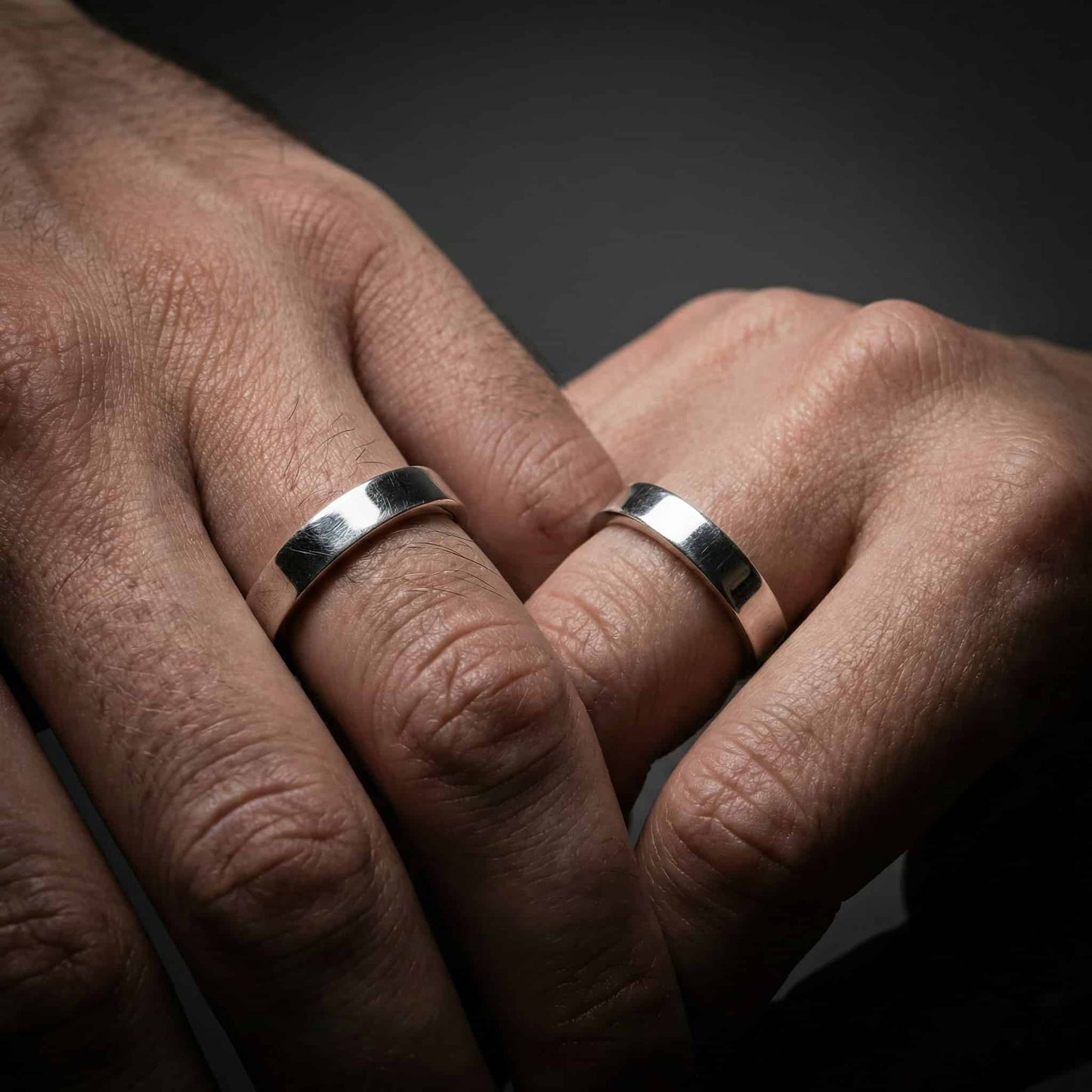 Pareja de novios con alianzas cuadradas originales el día de la boda.