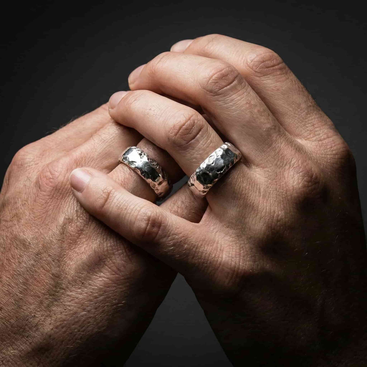 Pareja de novios con anillos de boda originales de plata pesada y ancha.
