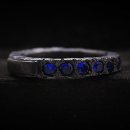 Detalle de la textura oxidada y piedras azules en anillo de estilo brutalista para hombre.