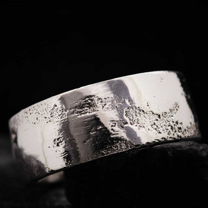 Primer plano macro de la textura forjada en arena sobre plata de ley, mostrando los detalles orgánicos.